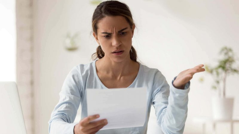 Woman looking exasperated holding up sheet of paper